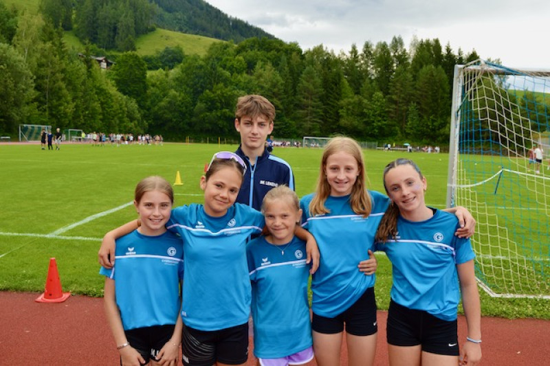 Leichtathletik-Nachwuchs in blauen Trikots posiert vor Fußballtor in den Alpen